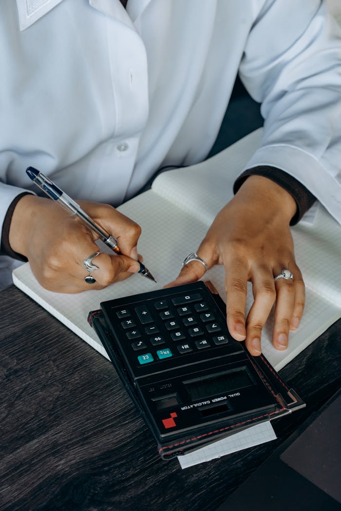 services-04 Close-up of hands writing in a notebook while using a calculator. Ideal for finance and business concepts.