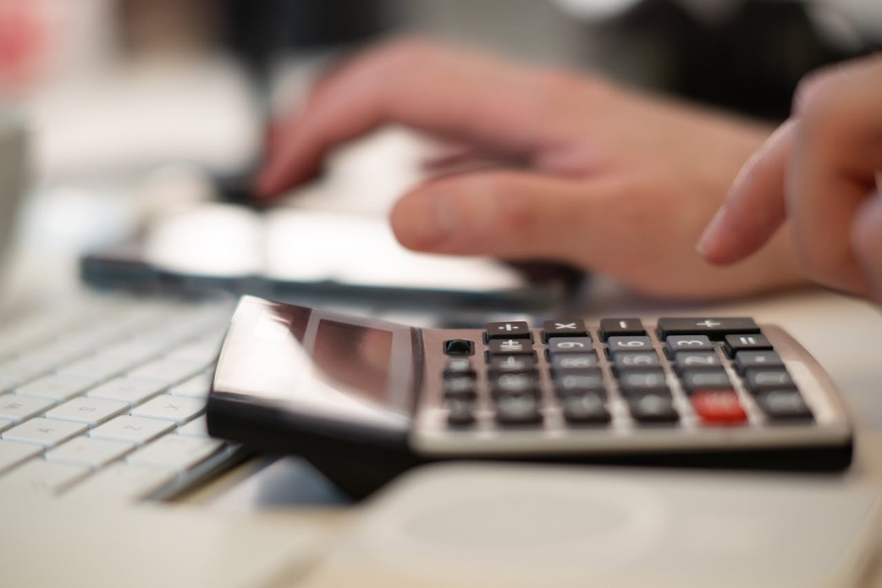 services-02 Close-up of hands using a calculator and keyboard in a financial setting, indoors.